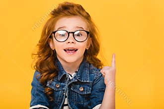 portrait of smiling little kid in eyeglasses pointing up