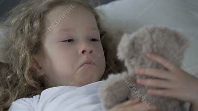 Orphan girl crying, looking at her teddy bear and dreaming about family