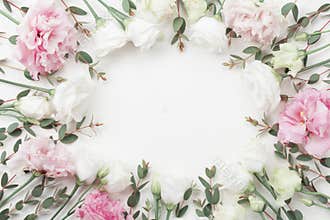 Beautiful floral frame of pastel flowers and eucalyptus leaves on white table top view. Flat lay style.