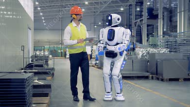 Human-like cyborg is getting switched on and set up by a male factory worker