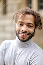Close up face of afro american smiling guy with brown curly hair.
