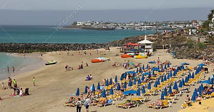 Deck chairs, umbrellas and bathers in Playa Dorada, Lanzarote, Canary Islands,