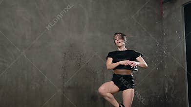 Contemporary dance under the rain. Wet girl dancer in black body suit makes rotation around herself on the stage under