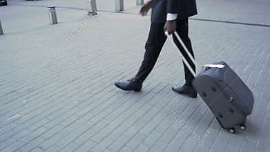 Businessman pulling suitcase at airport, business trip, first class travelling