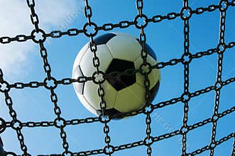 Soccer ball in chain net white and black football, blue sky