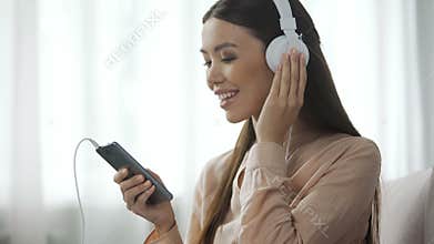Appealing woman listening music in headphones, loves radio station, enjoyment