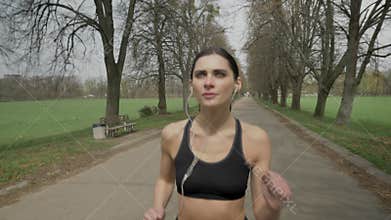 Young sport girl is running with earphones in park in summer, healthy lifestyle, sport conception