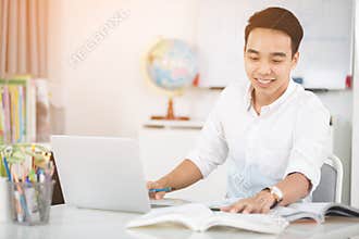 Young Asian man university student working with laptop computer.