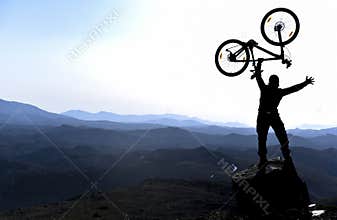 Man with bike standing on mountain ridge