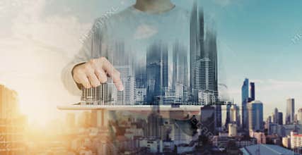 Double exposure, a man using digital tablet, and modern buildings hologram. Real estate business and building technology concept