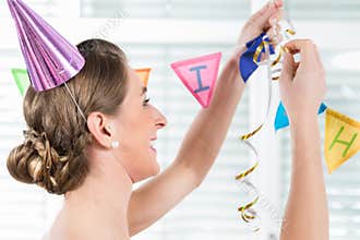 Happy adult woman hanging decorations for her birthday party