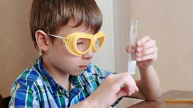 Experiments on chemistry at home. Boy knocks on a test tube with reagents using glass stick.