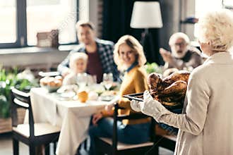 senior woman carrying thanksgiving turkey for holiday dinner