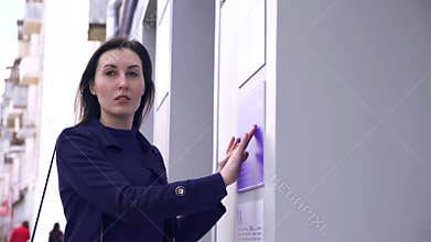 Blind girl on the street reading braille on an info plate on the building