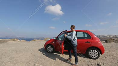 Young man driving car up to edge of abyss to look at enchanting landscape