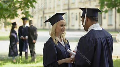Male, female graduates talking after ceremony, university education, adult life