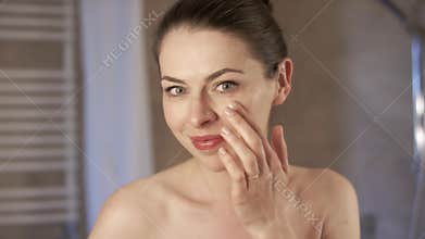 Lovely woman applying cream in morning