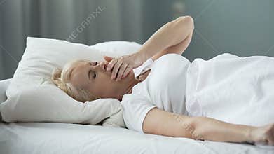 Pretty blond woman waking up, stretching hands and yawning, good morning