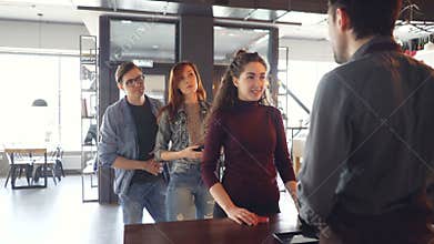 Talkative young woman is chatting with cashier at counter in cafe while impatient people are standing in line and