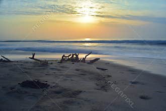 Beautiful long exposure photography of sunrise at sea shore with sea water coming over the sand