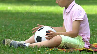 Lonely boy sitting in park with ball, no friends to play with, bullying problem