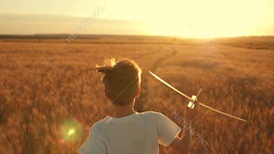 Happy child runs with a toy airplane on a sunset background over a field. The concept of a happy family. Childhood