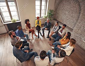Business people sitting at circle in board room and discussing