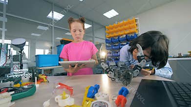 Kids constructing a toy robot. Two children construct a robot in a laboratory room.