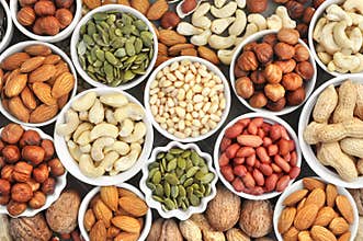 Colorful mix of nut and seed varieties: peanut, cashew, hazelnut, almond, pine nuts, walnut, pumpkin seeds; healthy diet snack