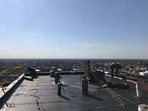 Roofer and a crew working on a smooth modified flat roof. Workers.