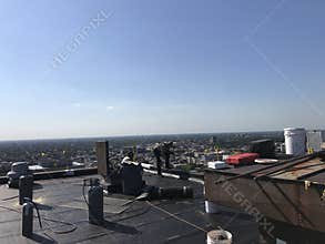 Roofer and a crew working on a smooth modified flat roof, roofing project in progress