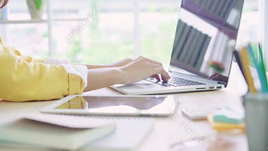 Beautiful young smiling asian woman working laptop on desk in living room at home.