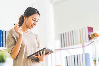 Asian girl working at home office using digital tablet, with copy space. Business owner entrepreneur, small business startup
