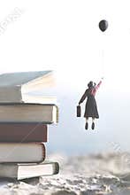 Woman carried by a balloon flies above a mountain of giant books