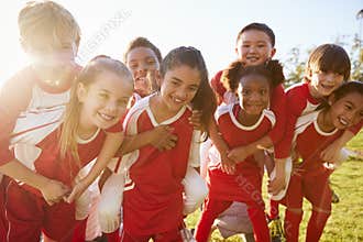 Kids in elementary school sports team piggybacking outdoors