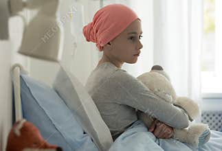 Sick child with cancer sitting in hospital bed