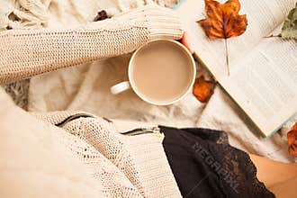 Woman in warm sweater and checkered plaid with cup of coffee latte in hands sitting with romantic books. Top view point.