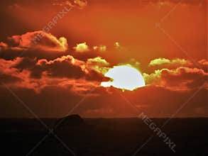 Dramatic Fiery Sun Surrounded by Clouds During Sunset
