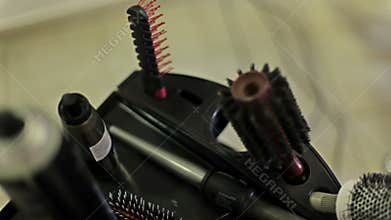 The hairdresser takes a hair spray from a table with combs, curling iron and other items for hair cutting and styling