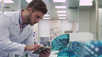 Man checks the work of lab device with tablet