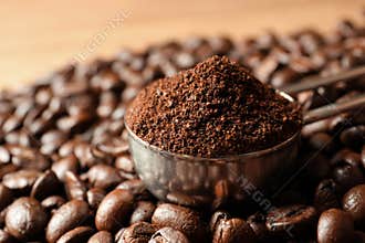 Spoon with coffee grounds and roasted beans on table