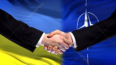 Ukraine and NATO handshake, international friendship relations, flag background