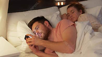 Man using smartphone while girlfriend is sleeping