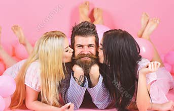 Alpha male concept. Threesome lay near balloons, happy guy on smiling face. Man with beard and mustache attracts blonde