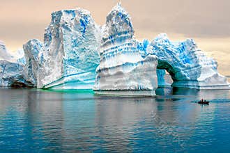 Iceberg in Antarctica, ice castle with Zodiac in front. Huge iceberg sculptured like fairytale castle