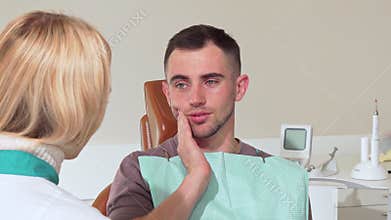 Male patient with toothache talking to his dentist at the hospital