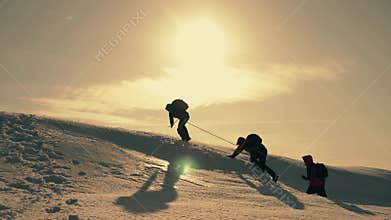 Tourists climbing a mountain snow cliff. Stretching a helping hand. People help each other. Teamwork, teamwork concept