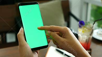 4K footage. close up woman hand holding smart phone with green screen at coffee shop, using finger touch on phone screen