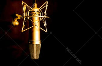 Golden color microphone detail in music and sound recording studio, black background, closeup