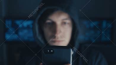 Crime Hacker in hood writing message on cell phone